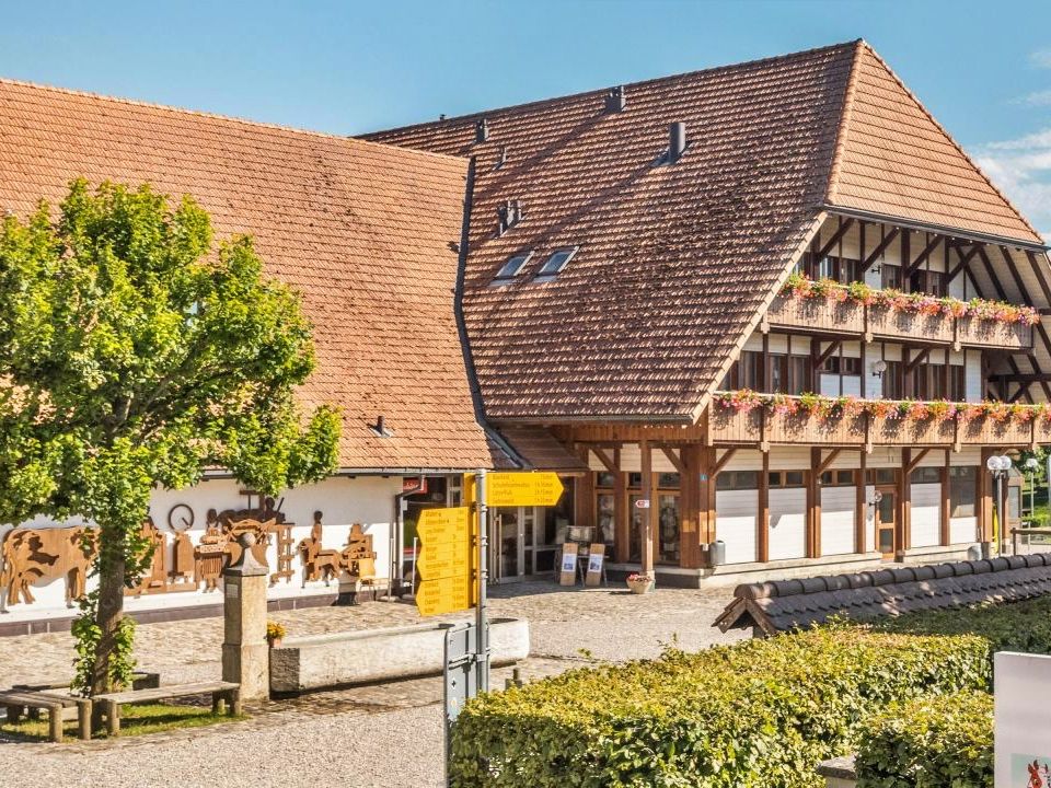 Emmentaler Schaukäserei von aussen mit Blüten und Zieranlage.