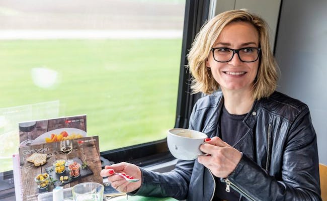 Reizigers in de trein: Genietmoment met koffie en uitzicht op het Zwitserse landschap