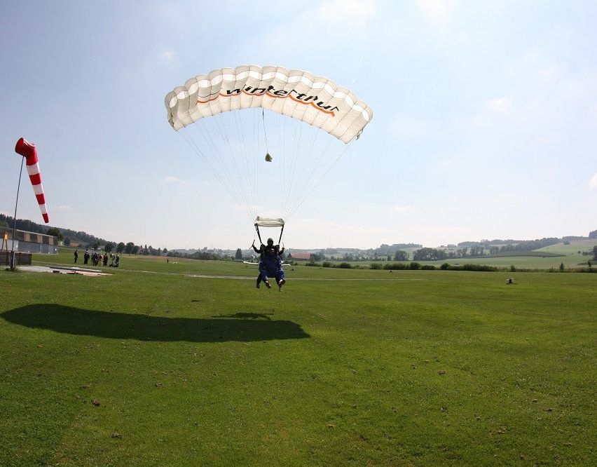 Lompat payung di Luzern dengan parasut di atas lapangan hijau