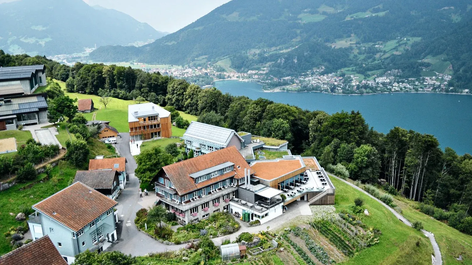 Отель Filzbach с видом на озеро, окружённый горами и лесами.