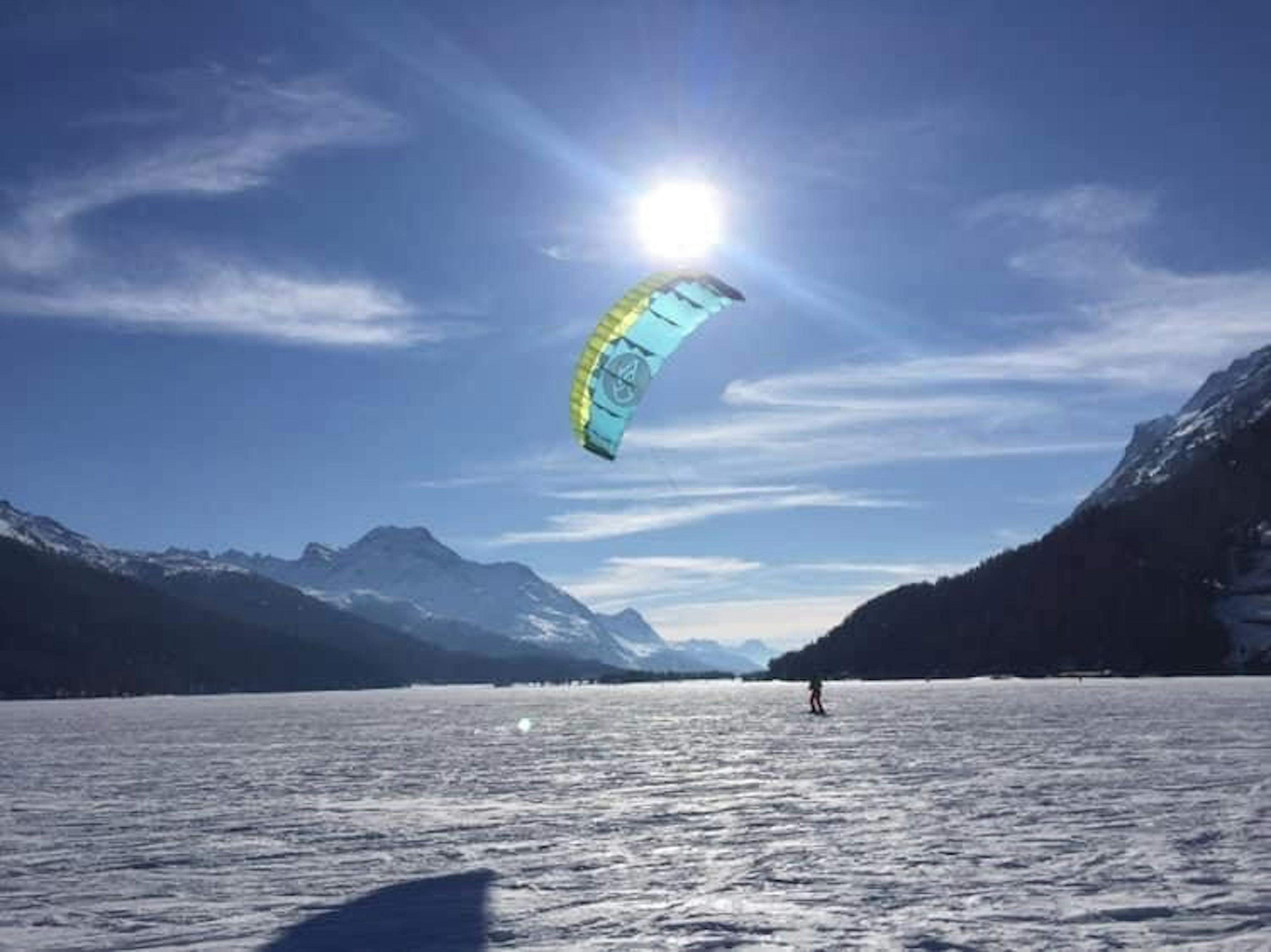 Kitesurfen auf Schnee in den Bergen im Winter, ideal für Abenteuer und Gruppenaktivitäten.