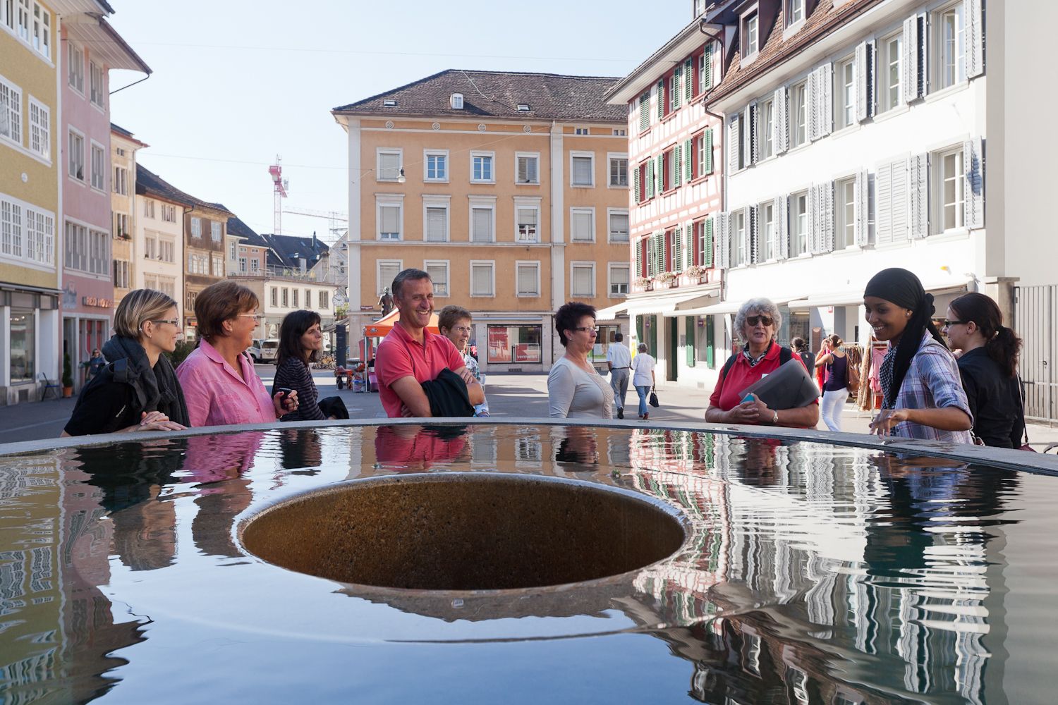 Visitors surround a water feature in the city of Frauenfeld on a sunny autumn day.