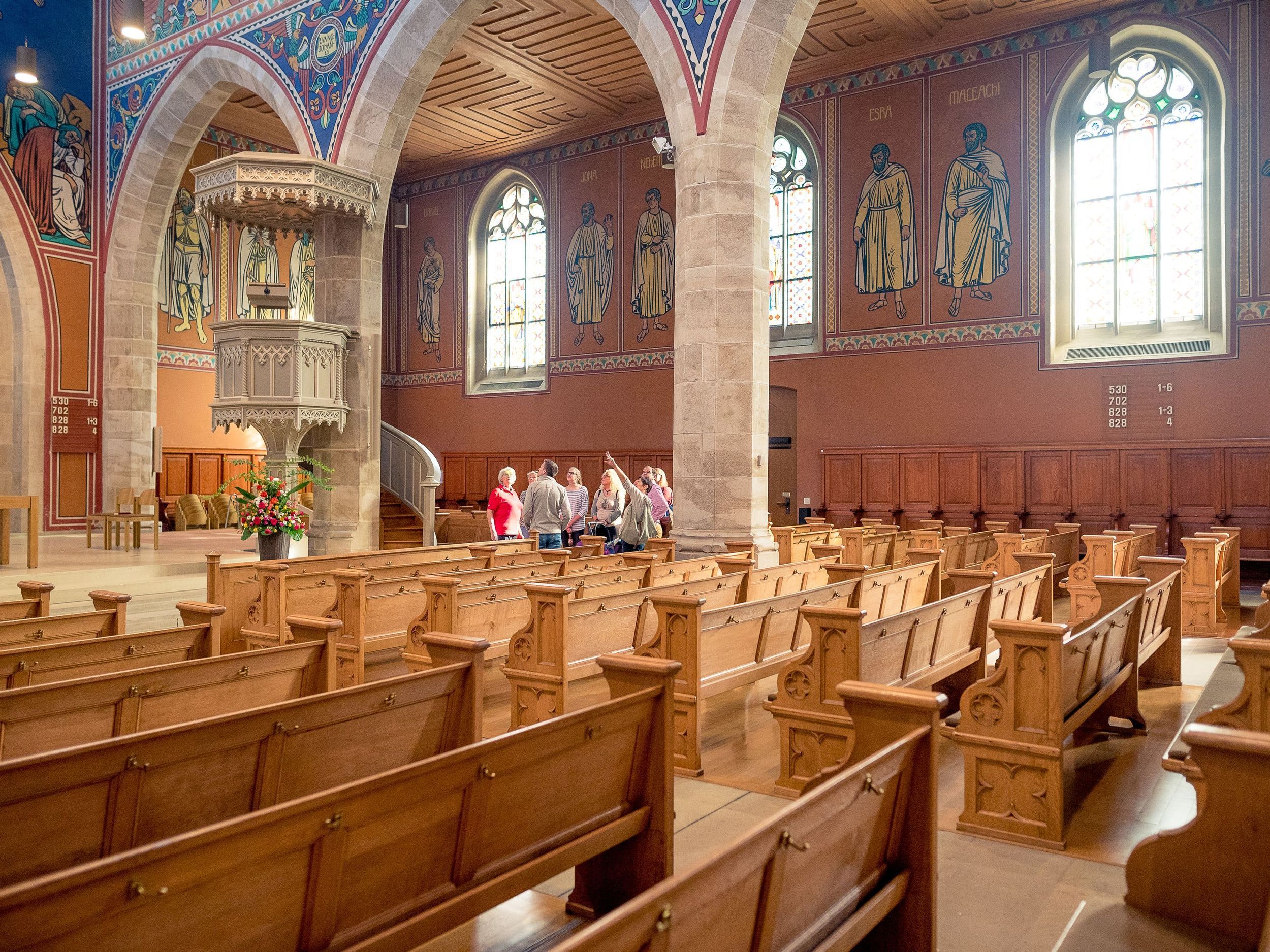 Interior view of the Frauen Tower with visitor groups, rows of wooden benches, historic church.