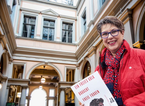 Kobiety prezentują plakat z przesłaniem w zabytkowym budynku.