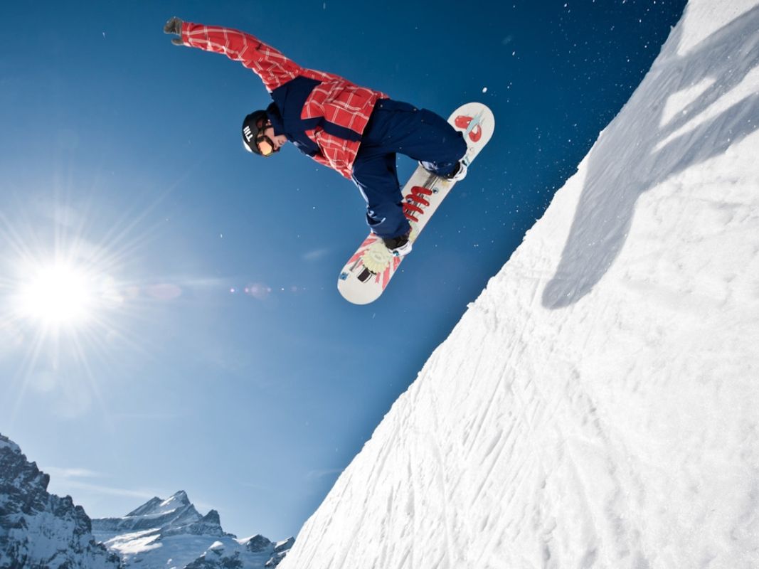 自由式滑雪者在阿尔卑斯山的雪崖上跳跃。