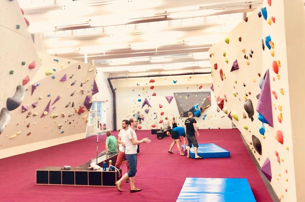 Freiruum bouldermatta: Klättrare tränar på färgglada klätterväggar på röd matta.