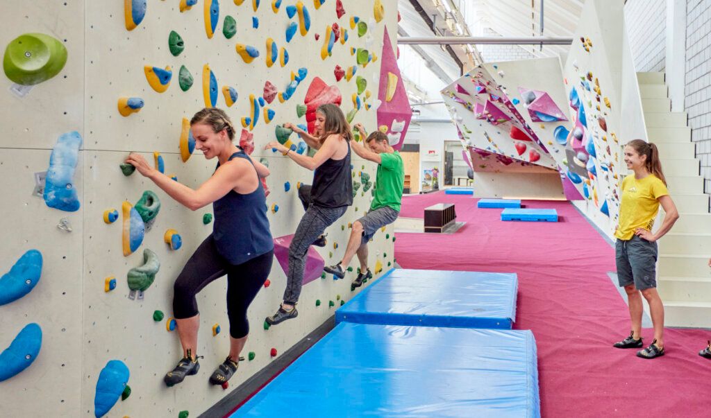 Freiruum Boulder-område: Personer som klättrar på bouldermuren, blå mattor, inomhus.