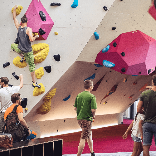 Freiruum klätterområde med klättrare på väggen, gäster som tittar på aktiviteten