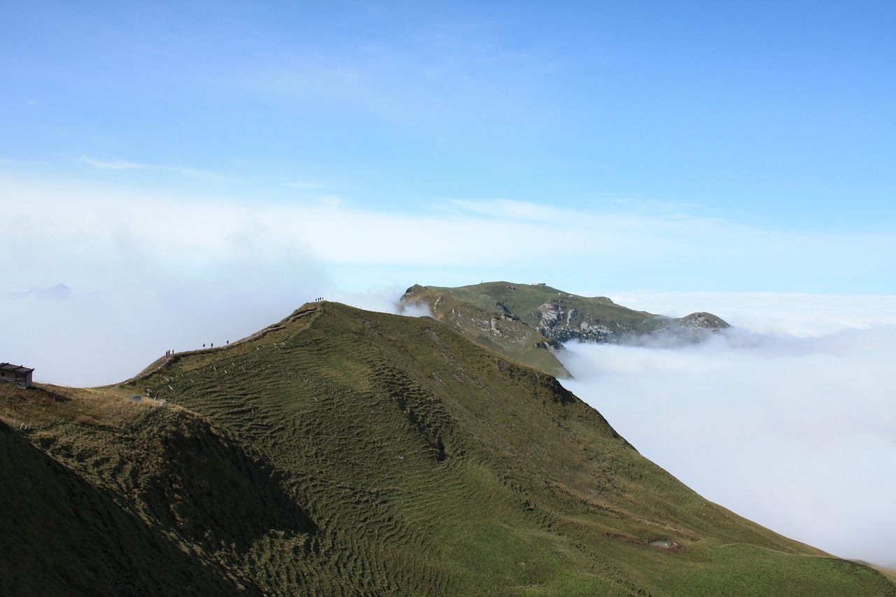 Fronalpstock view with fog limit in 2023. Green hills, blue sky, blurred fog region.