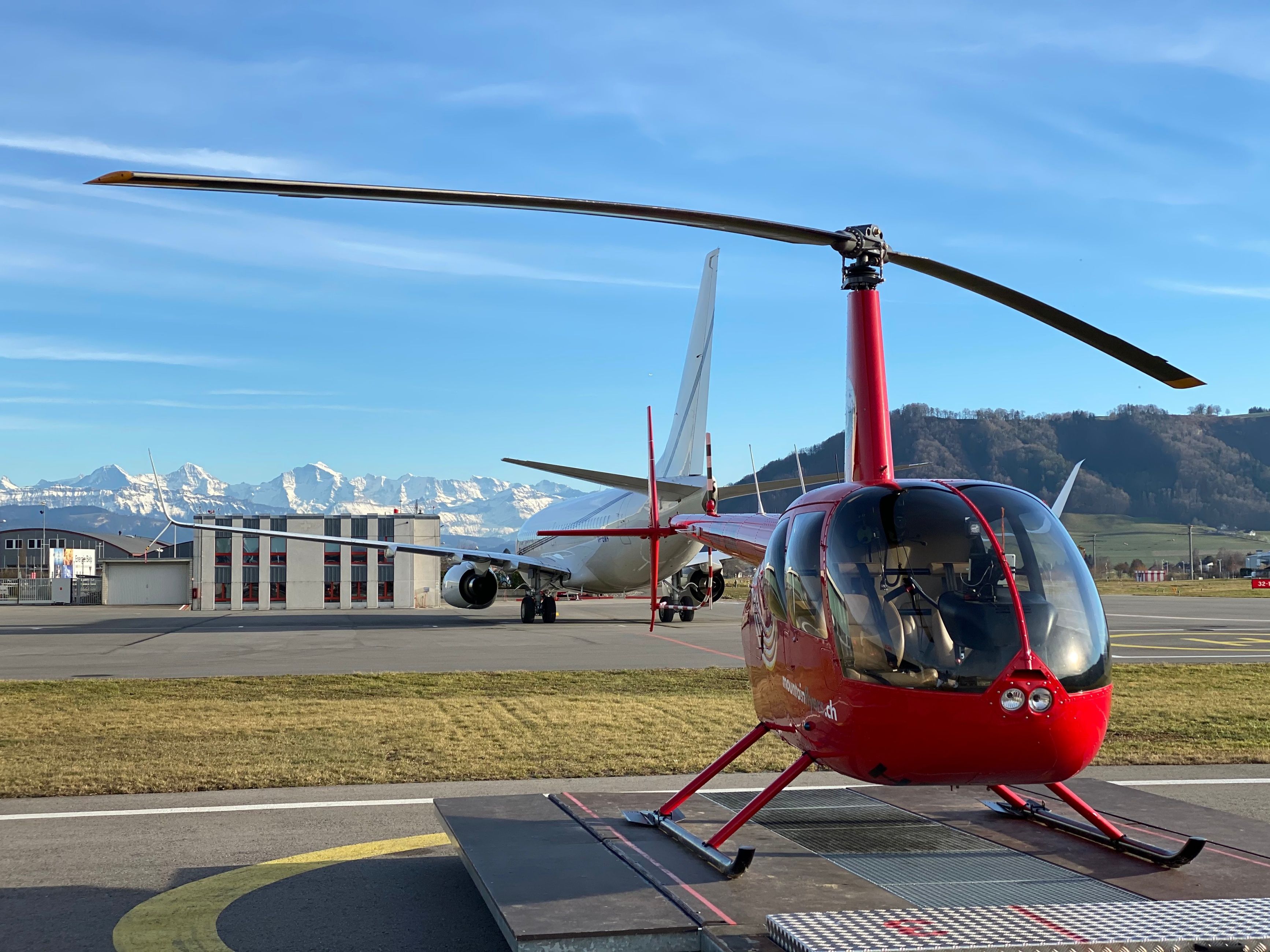 Zábavné+lety+helikoptérou+na+letišti+s+výhledem+na+Švýcarské+Alpy+a+modrou+nebeskou+oblohu.