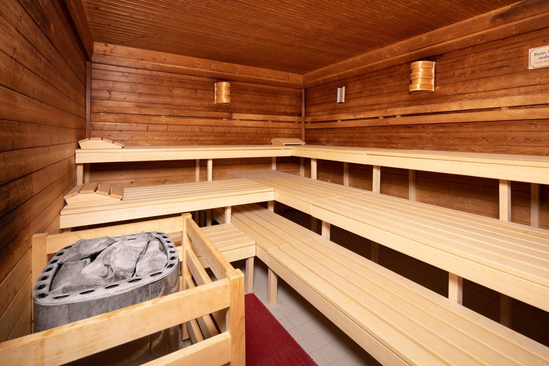 Sauna Grindelwald avec des bancs en bois et un poêle, atmosphère conviviale.