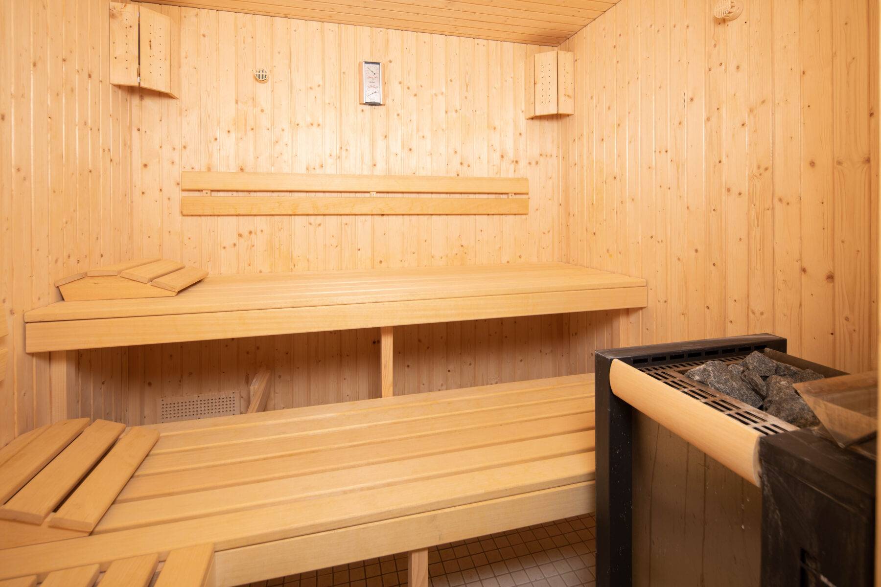 Sauna Grindelwald avec des bancs en bois et un poêle, atmosphère confortable.