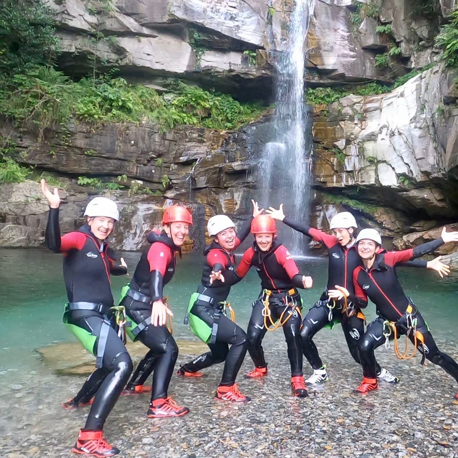 बोगेरा कैन्योनिंग: जलप्रपात के सामने नियोप्रीन सूट में समूह, प्राकृतिक साहसिक के लिए आदर्श।