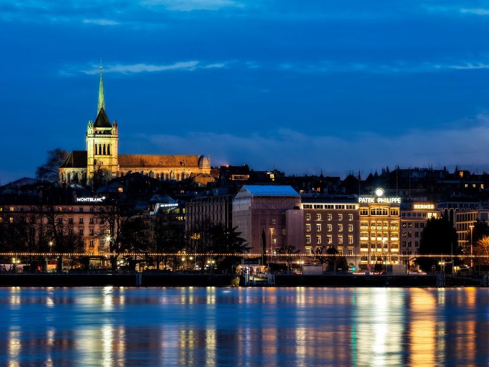 Genewa nocą: światła miasta odbijające się w wodzie, zabytkowe budynki i romantyczny nastrój.