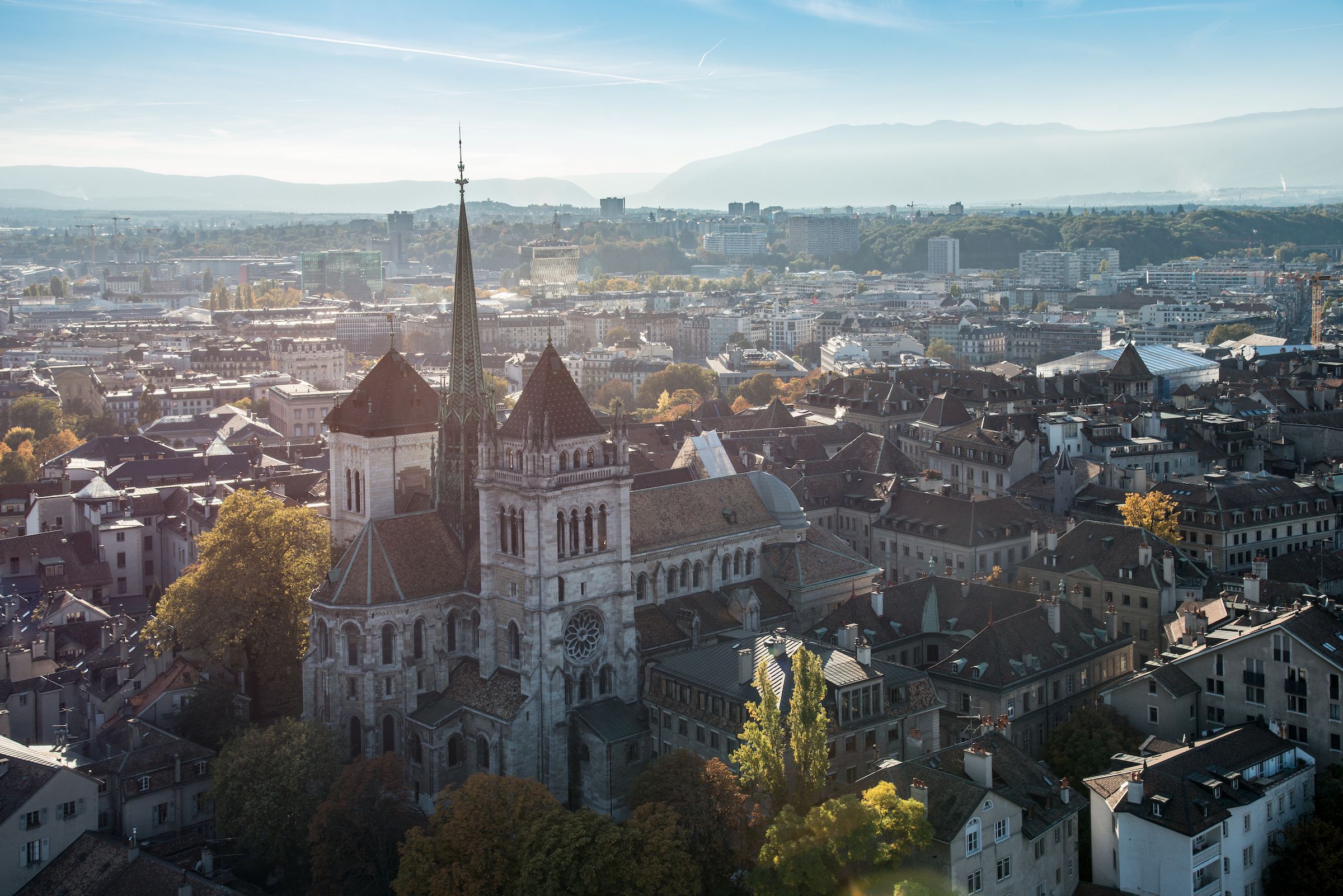 Genève città con edifici storici e montagne sullo sfondo.