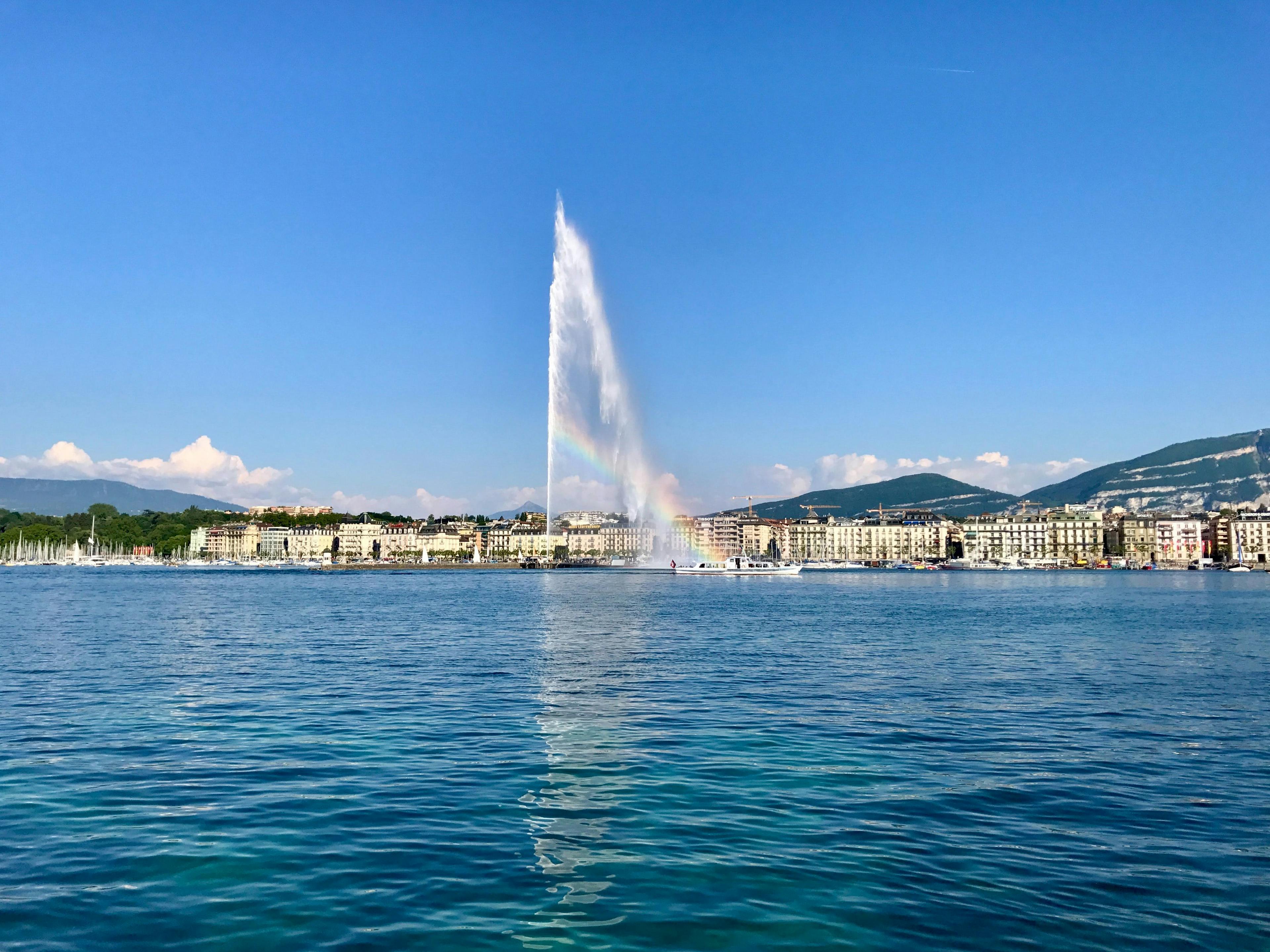 Genève spectacle d'eau dans le port avec arc-en-ciel, ciel bleu et paysage urbain.