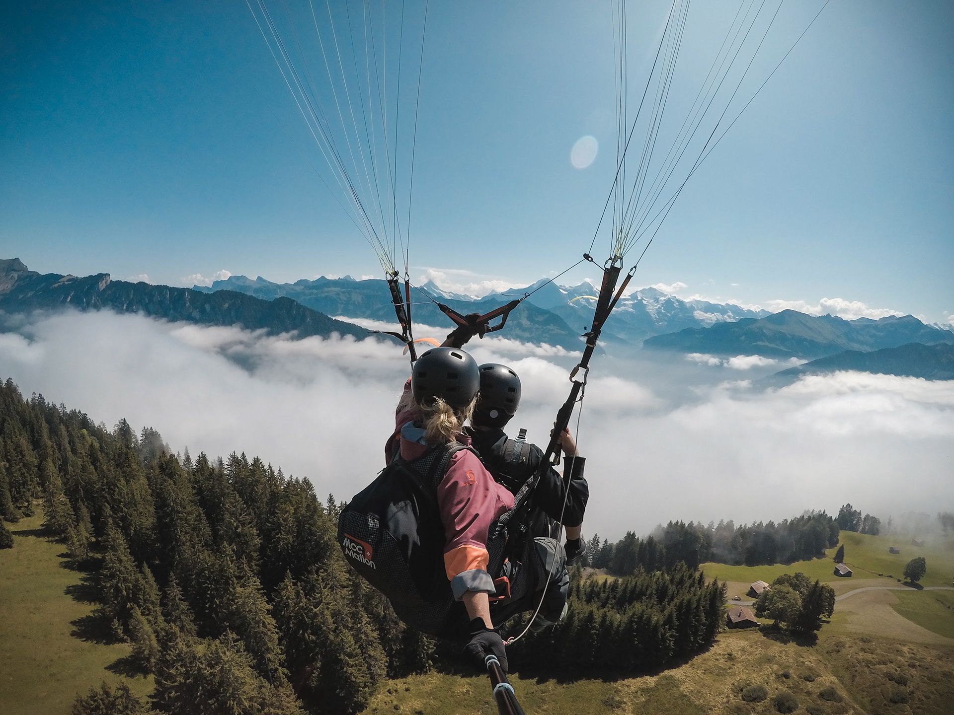 Senhora-Piloto desliza com parapente sobre nuvens e montanhas, vista clara, verão