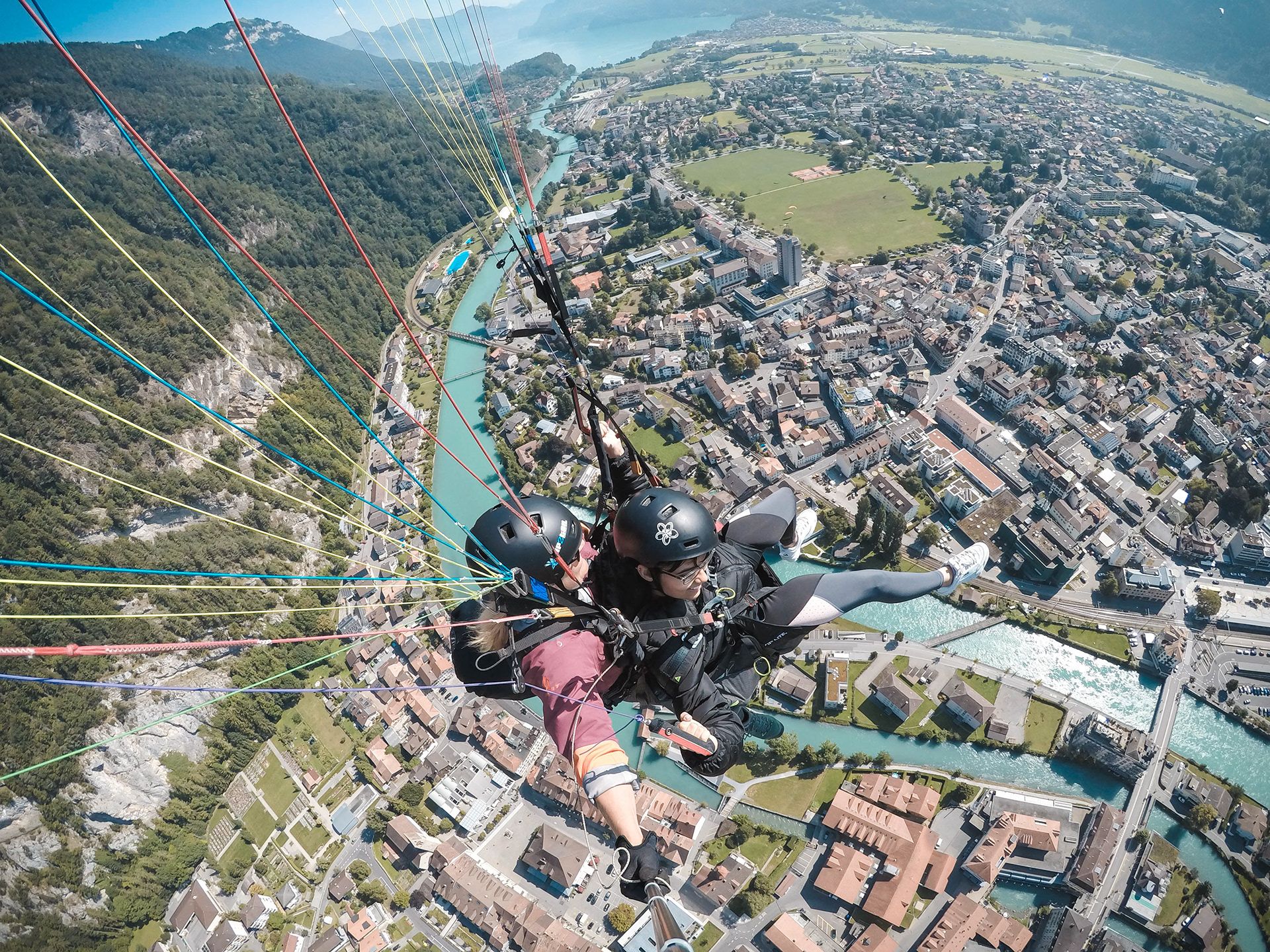 Piloto de parapente feminino voa sobre a cidade na região de Berna, vista para casas e rio