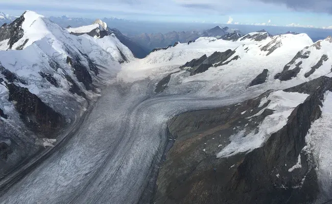Glaciärflygning över imponerande glaciärlandskap, majestätiska berg och isiga vidder. Klar sikt över snötäckta toppar.