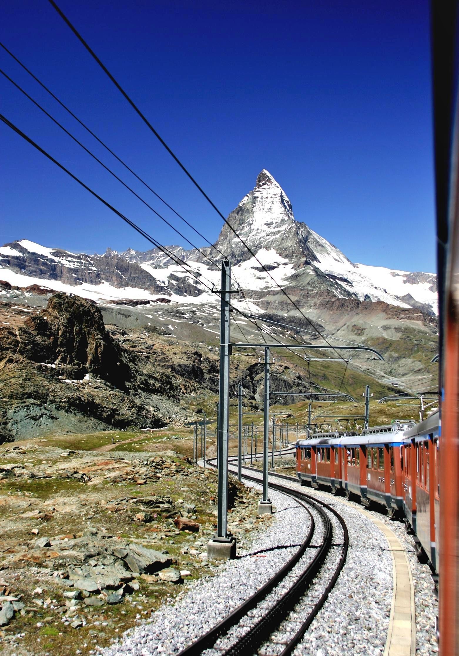 Gornergratbahn Zermatt berjalan di lalu lintas berkelok-kelok melalui pemandangan alpine.