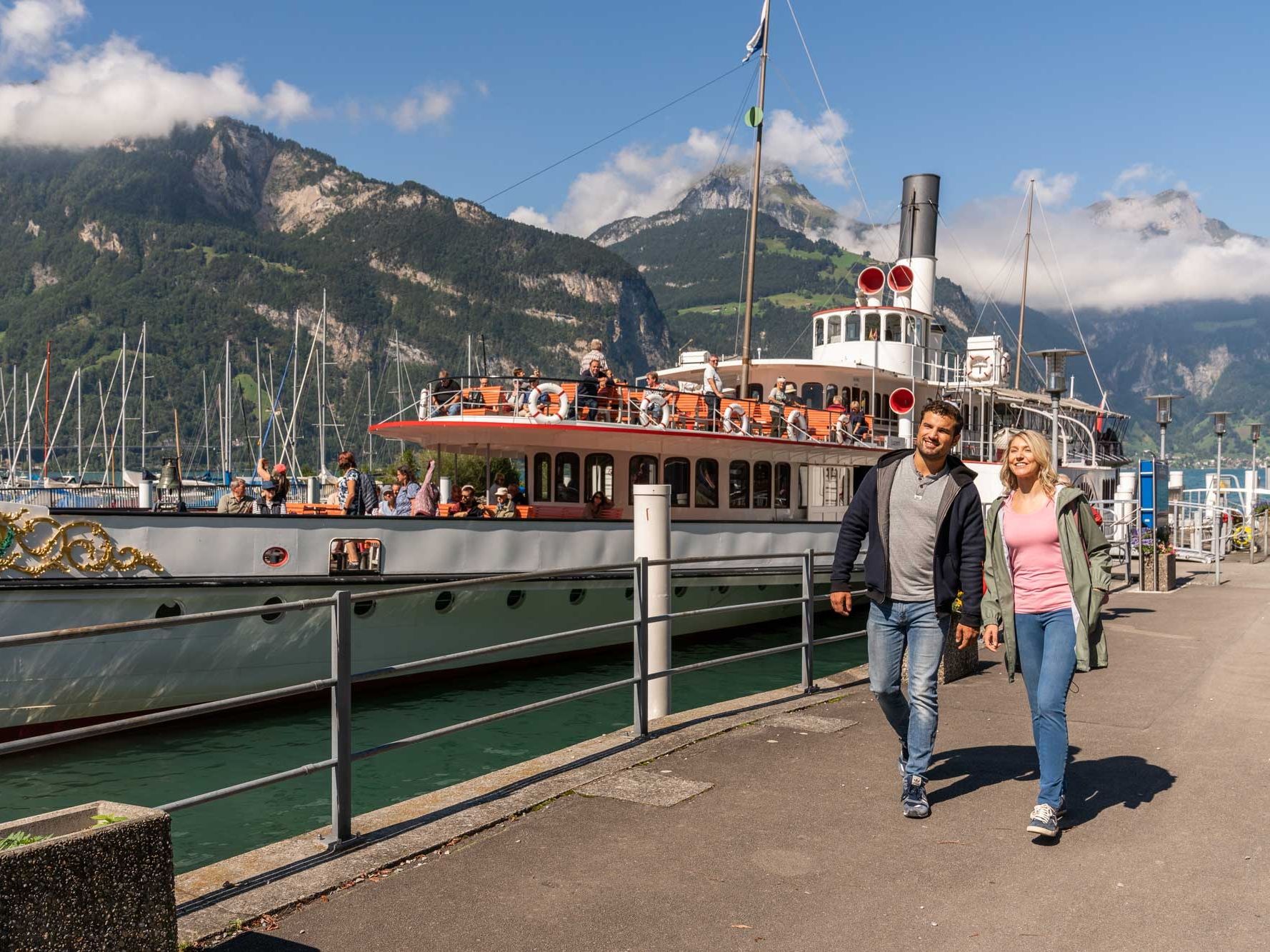 قارب في فلولين، يعبر من أمام منظر جبلي مذهل. هناك مسافرون على متنه.