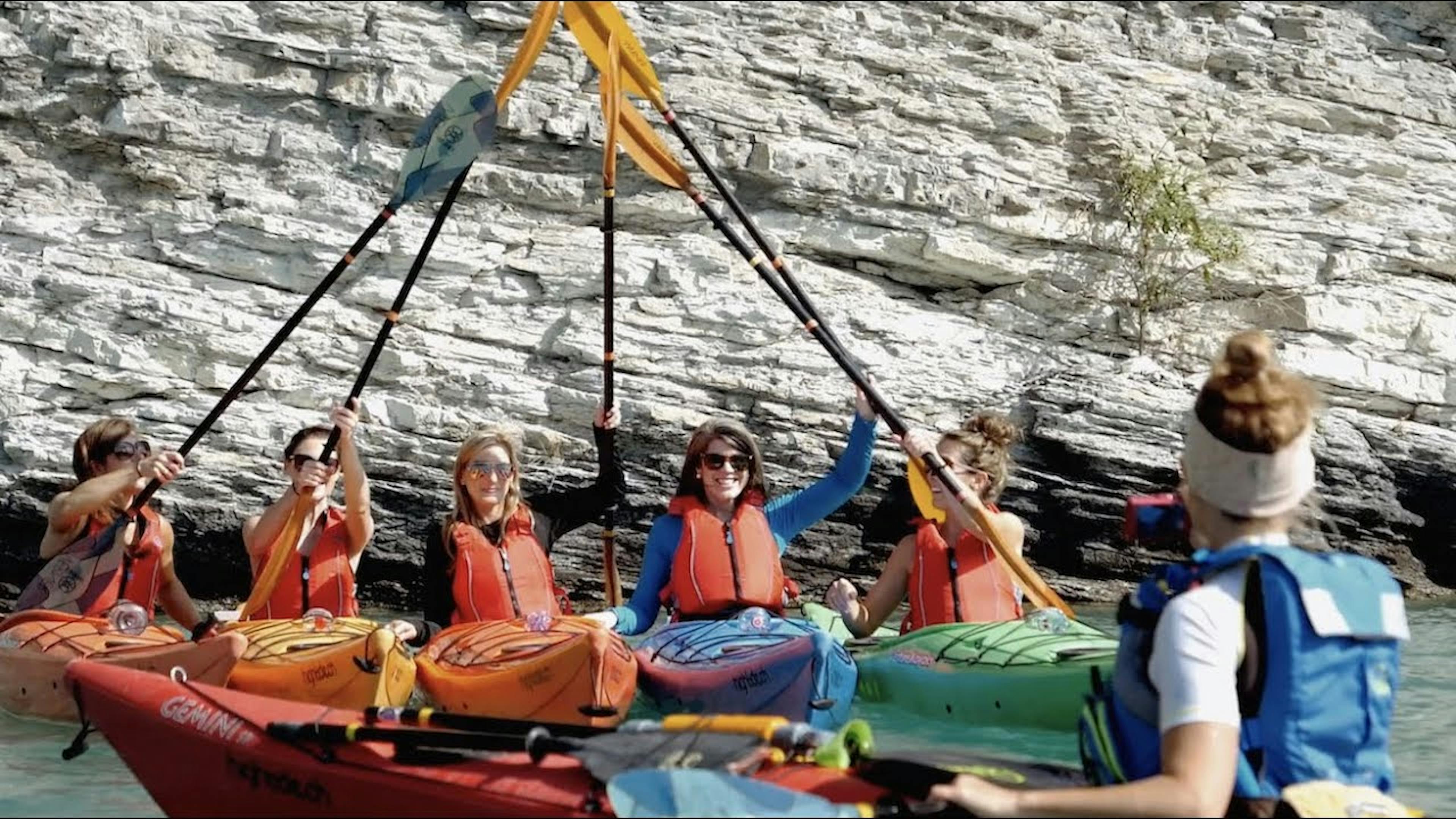 Gruppentour Kajak am Brienzersee, Teilnehmer in verschiedenen Kajaks, Felsen im Hintergrund