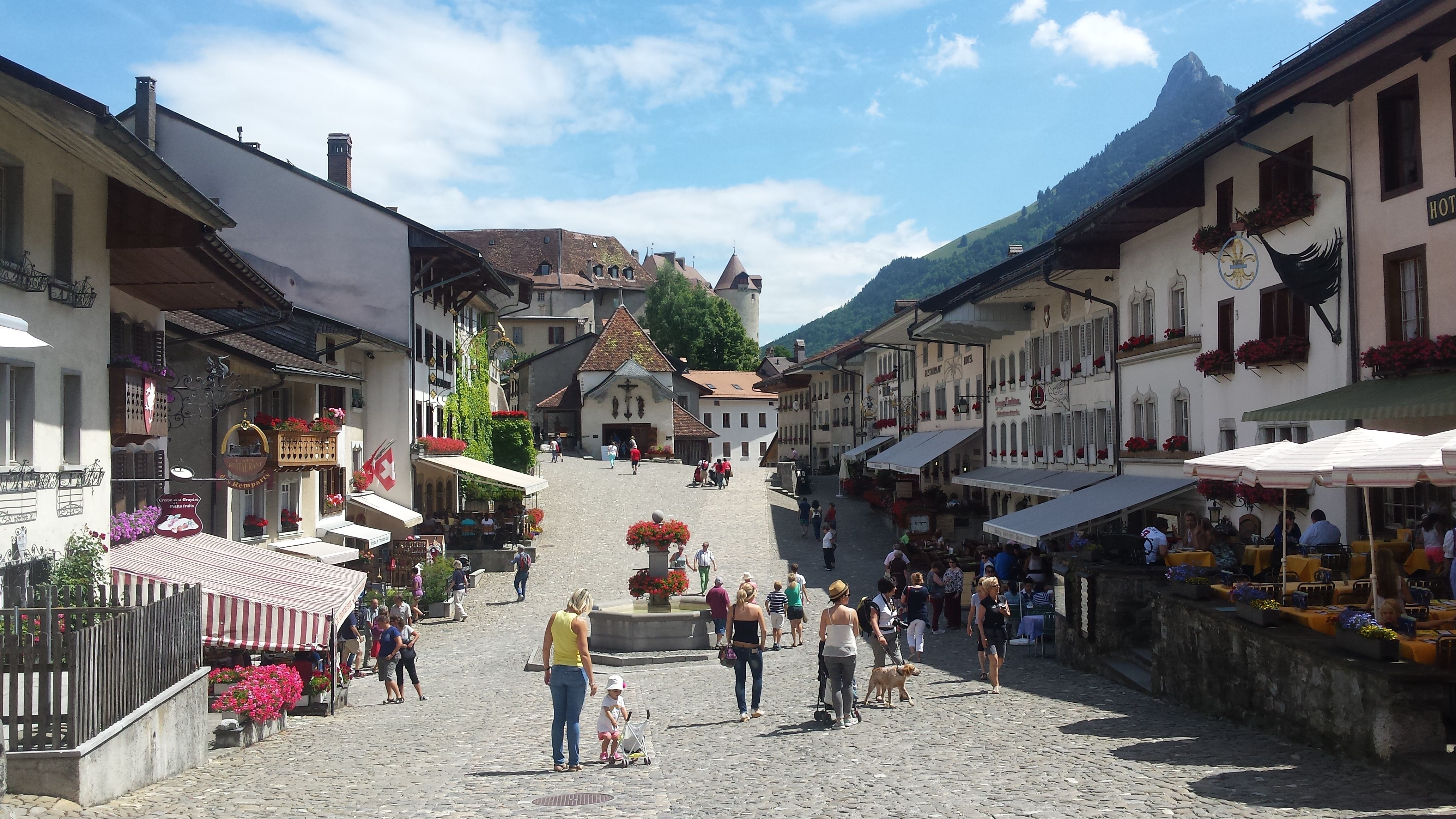 Kota Gruyère di pusat kota selama musim panas 2023 dengan pengunjung dan dekorasi floral.