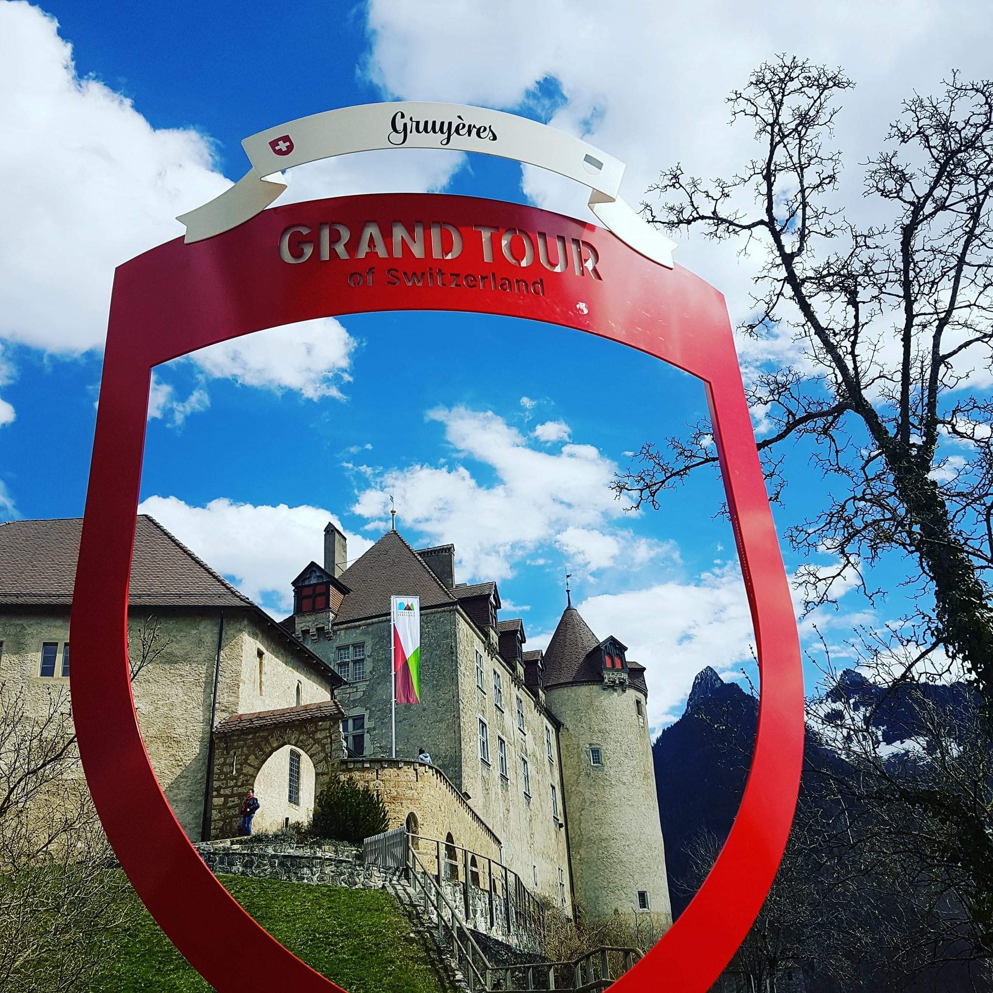 Lambang keju Gruyère dan cokelat di bawah langit biru.