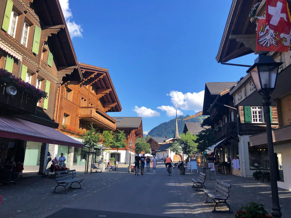 Gstaad: malerische Straßen mit traditionellen Holzhaeusern im Sommer mit Bergen und Natur
