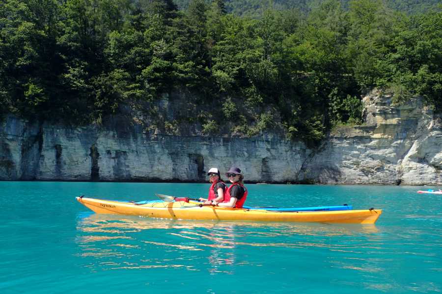 Kajakarstwo na Jeziorze Bodeńskim, dwie osoby w kajaku, turkusowa woda, otaczające skały.