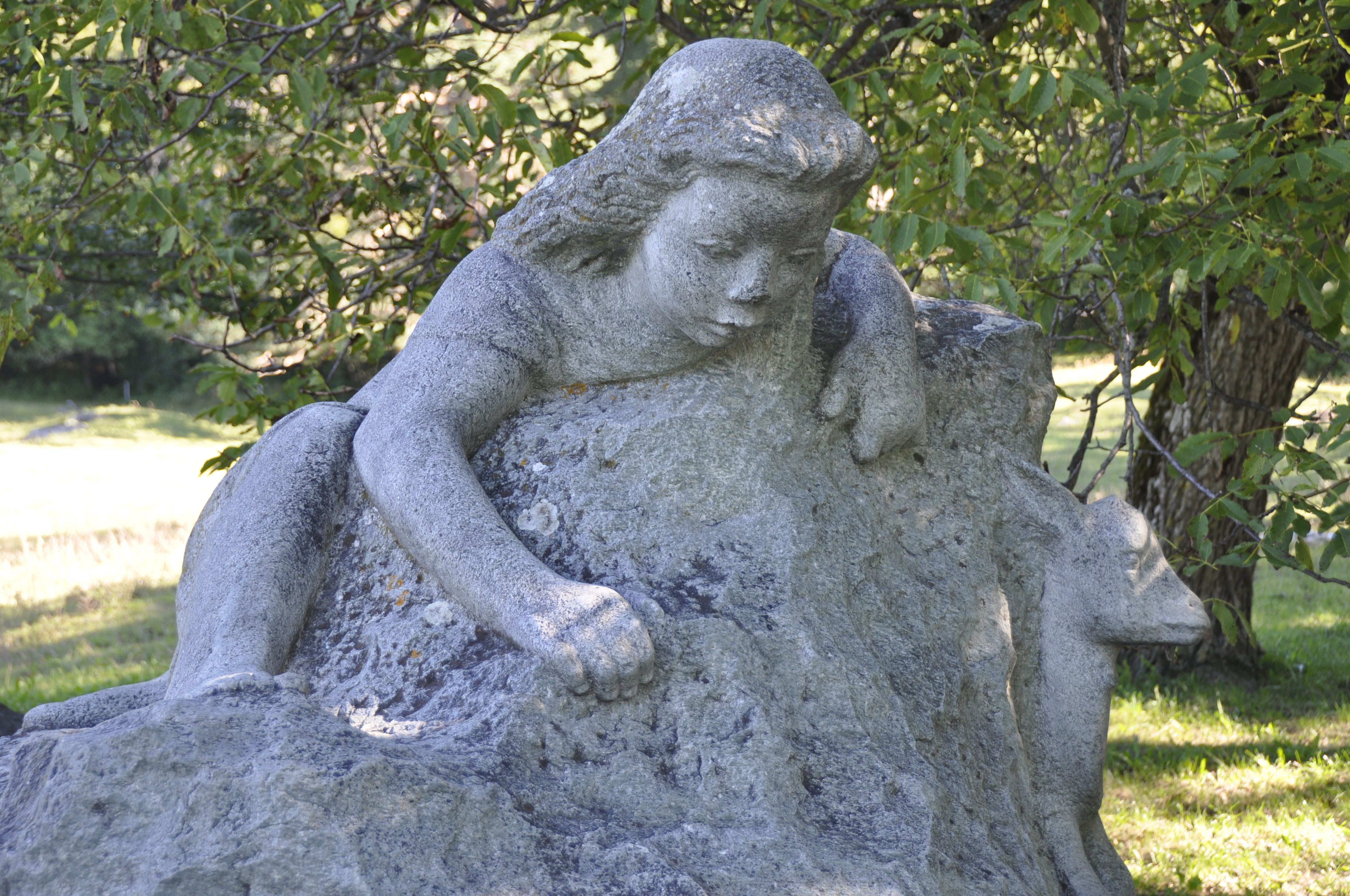 La scultura Heidibrunnen mostra una figura seduta su una pietra, circondata da alberi e prati