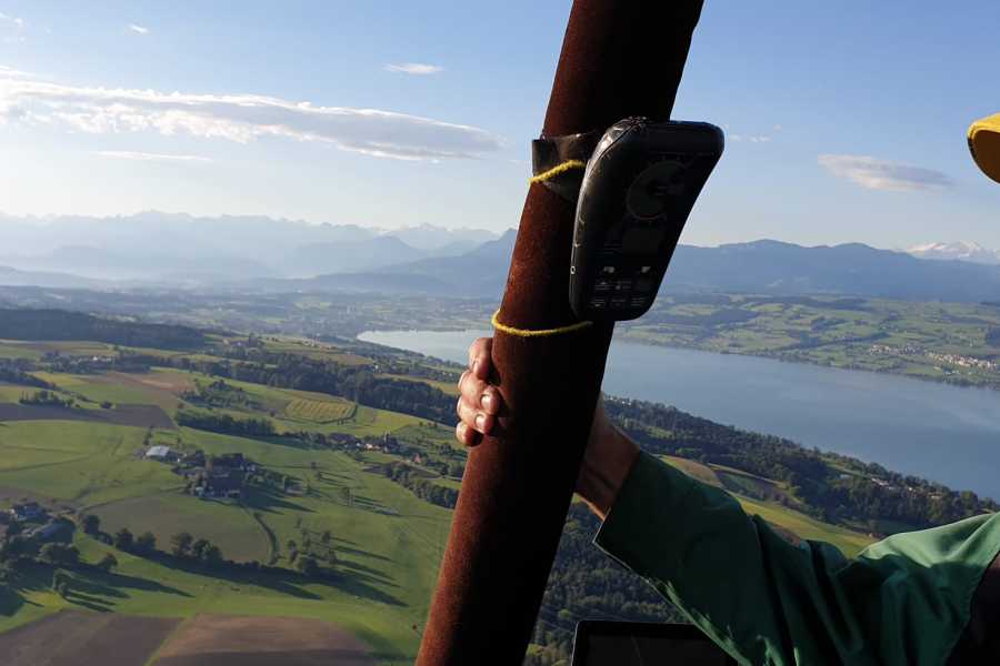 Balon udara menawarkan pemandangan Danau Bodensee, hamparan rumput hijau, dan pegunungan di latar belakang.