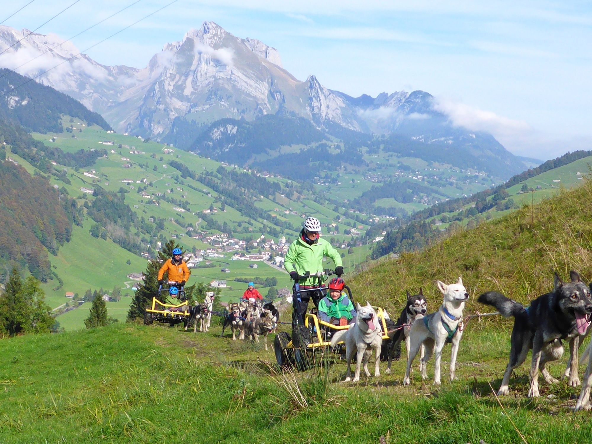 Huskystuff: Træning af logrer med hunde i bjergene under strålende vejr og afslappet gruppesamling.