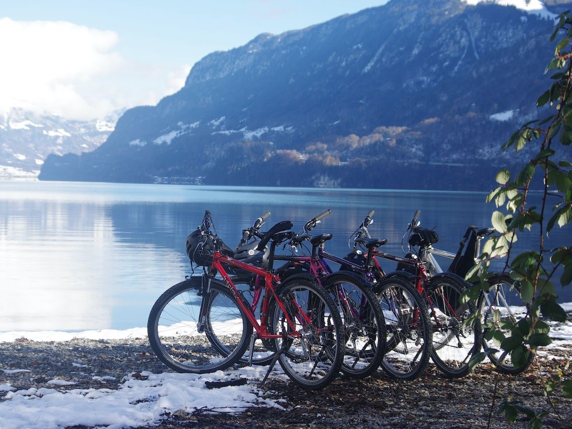 Passeio de bicicleta à beira do lago com uma natureza deslumbrante e montanhas ao fundo para uma recuperação ativa na natureza.