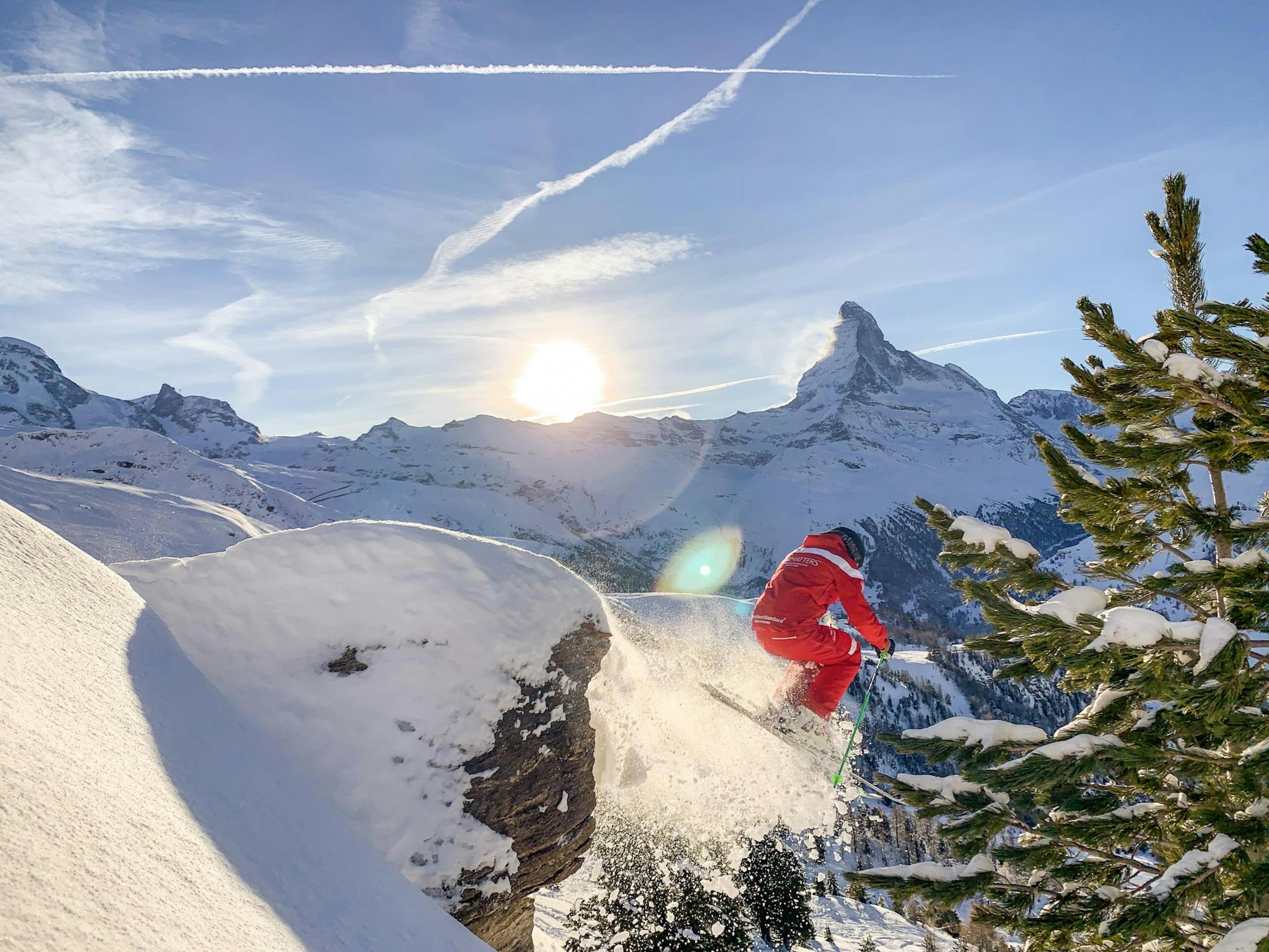 Freeride: Salto con gli sci davanti al Cervino in un paesaggio invernale, ideale per avventure e attività di gruppo.