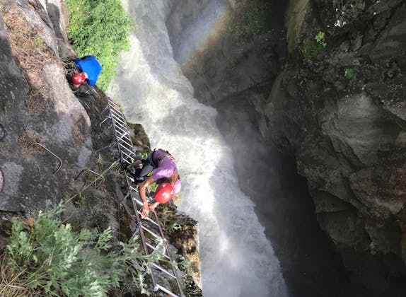 Rrugë alpinizmi në Gorge Alpine me alpinistë, një ujëvarë mahnitëse në sfond