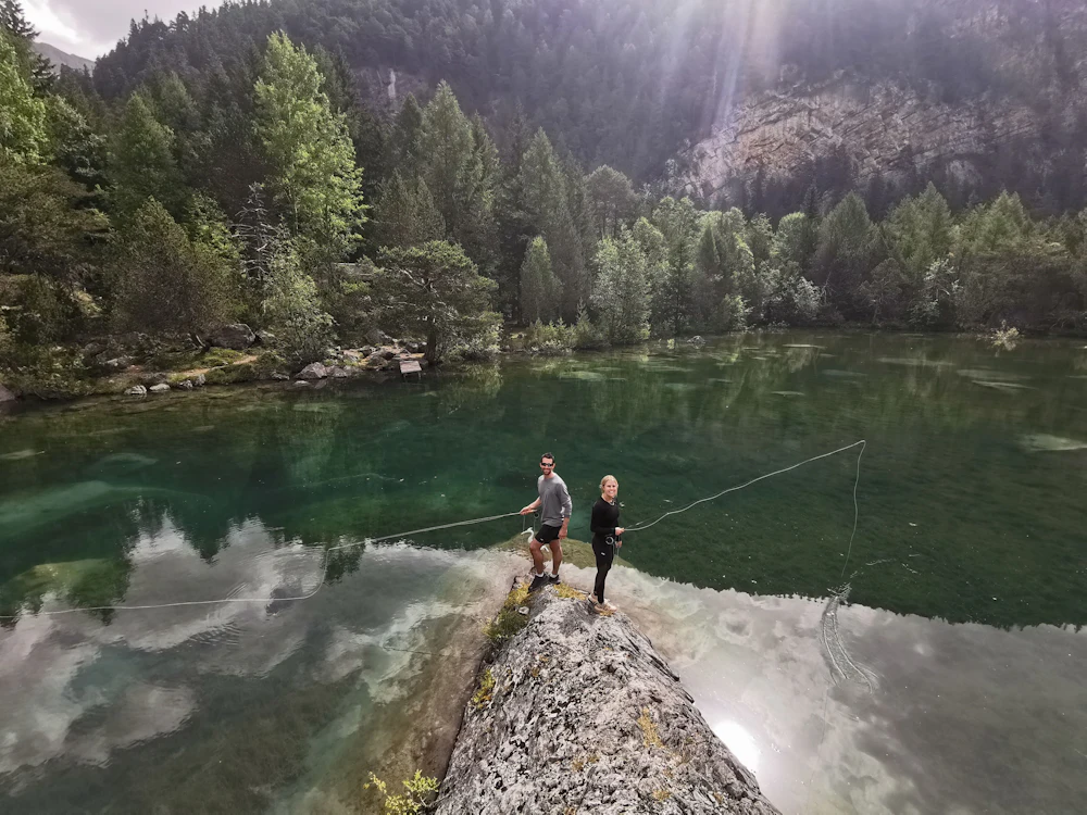 Pêche à la mouche suisse : deux pêcheurs au bord du lac clair dans la nature de Derborence, idéal pour l'aventure.