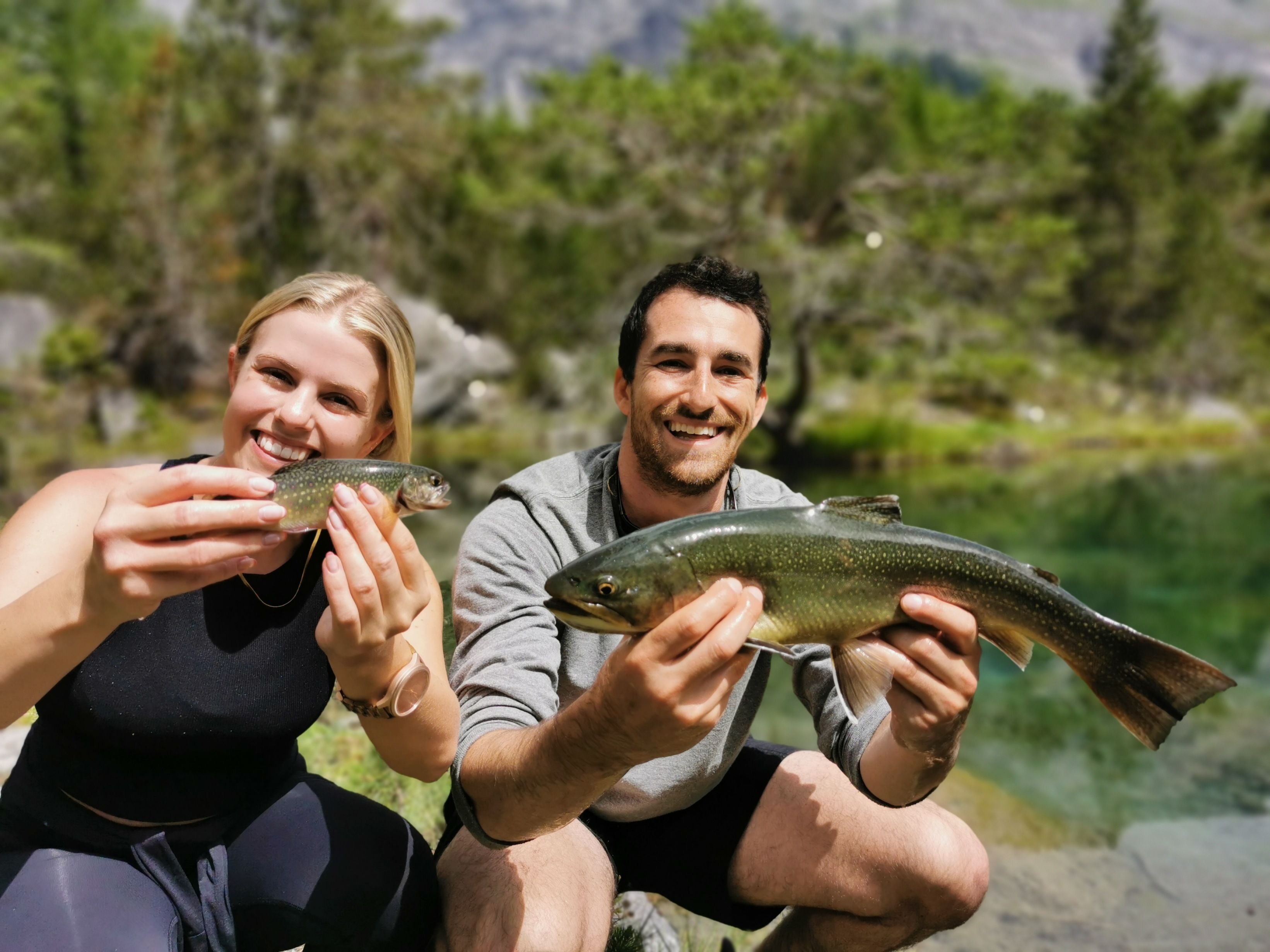 Fiske: Friskt fångst av två vänner vid lugn sjö på sommaren
