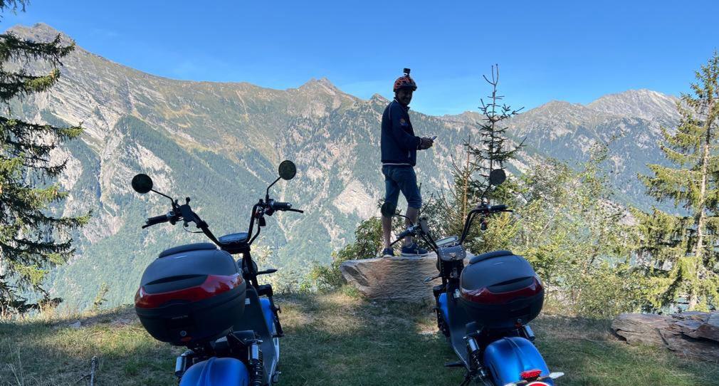 ticinoquad: Motociclista com vista para montanhas e natureza no verão, perfeito para aventuras e atividades em grupo.