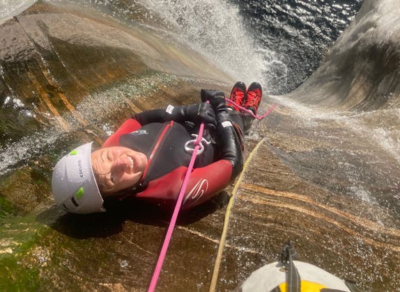 Canyoning à Nala : Une personne glisse joyeusement le long d'une cascade, aventure dans la nature.