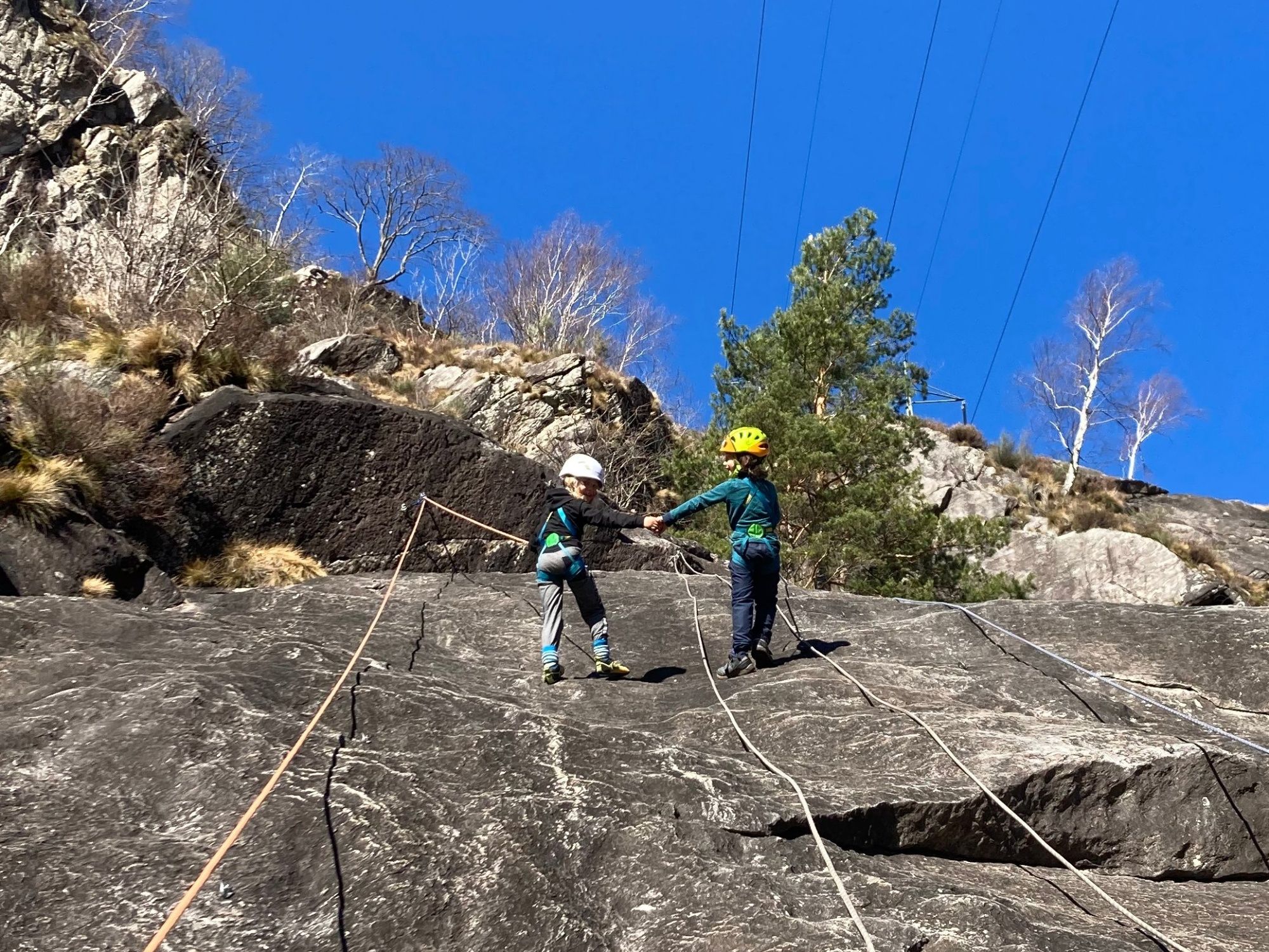 تسلق العائلات: الأطفال يتسلقون على صخرة في الطبيعة تحت سماء زرقاء