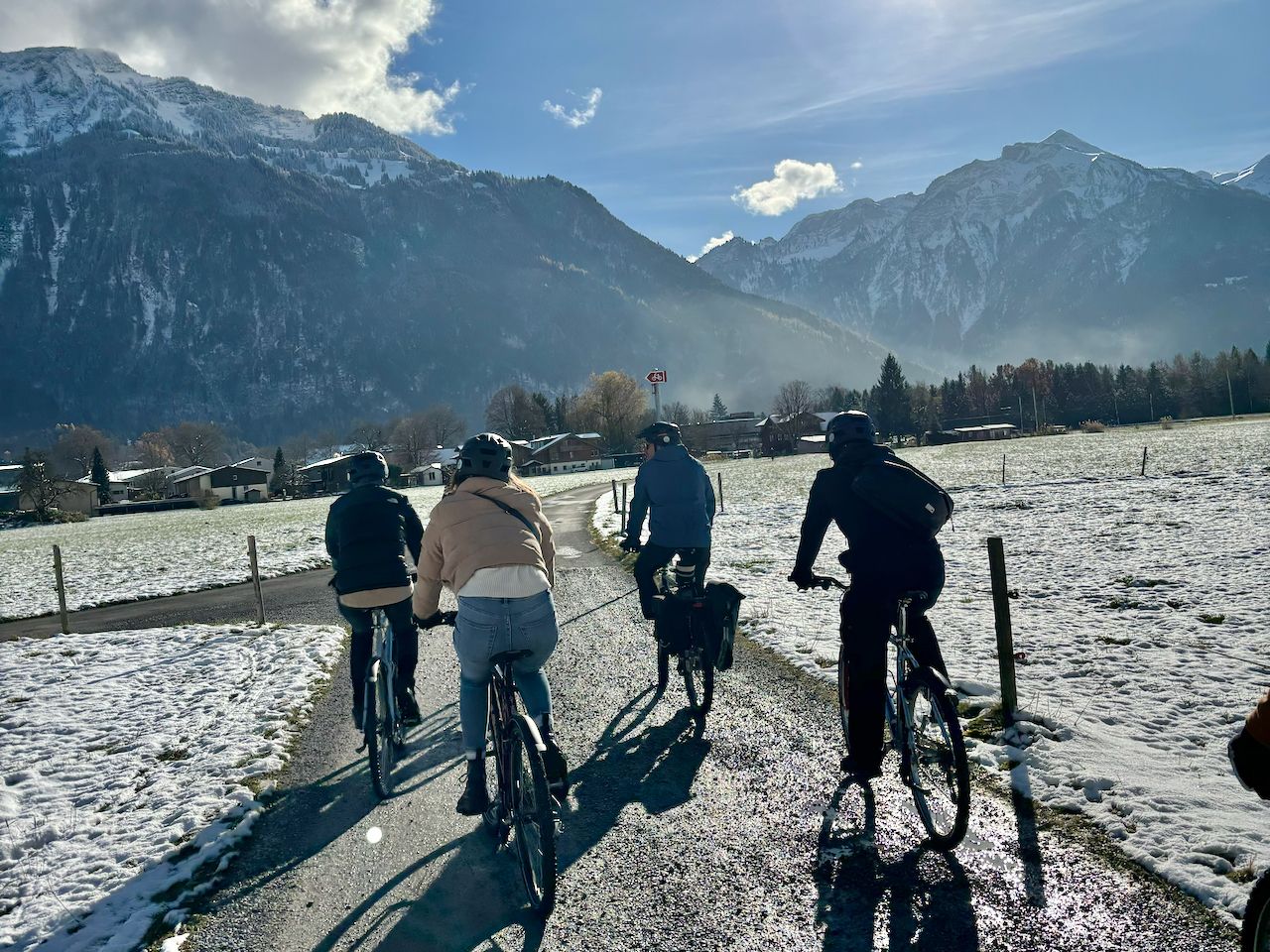 Passeio de bicicleta nas montanhas com amigos, cercado por paisagens cobertas de neve no inverno.