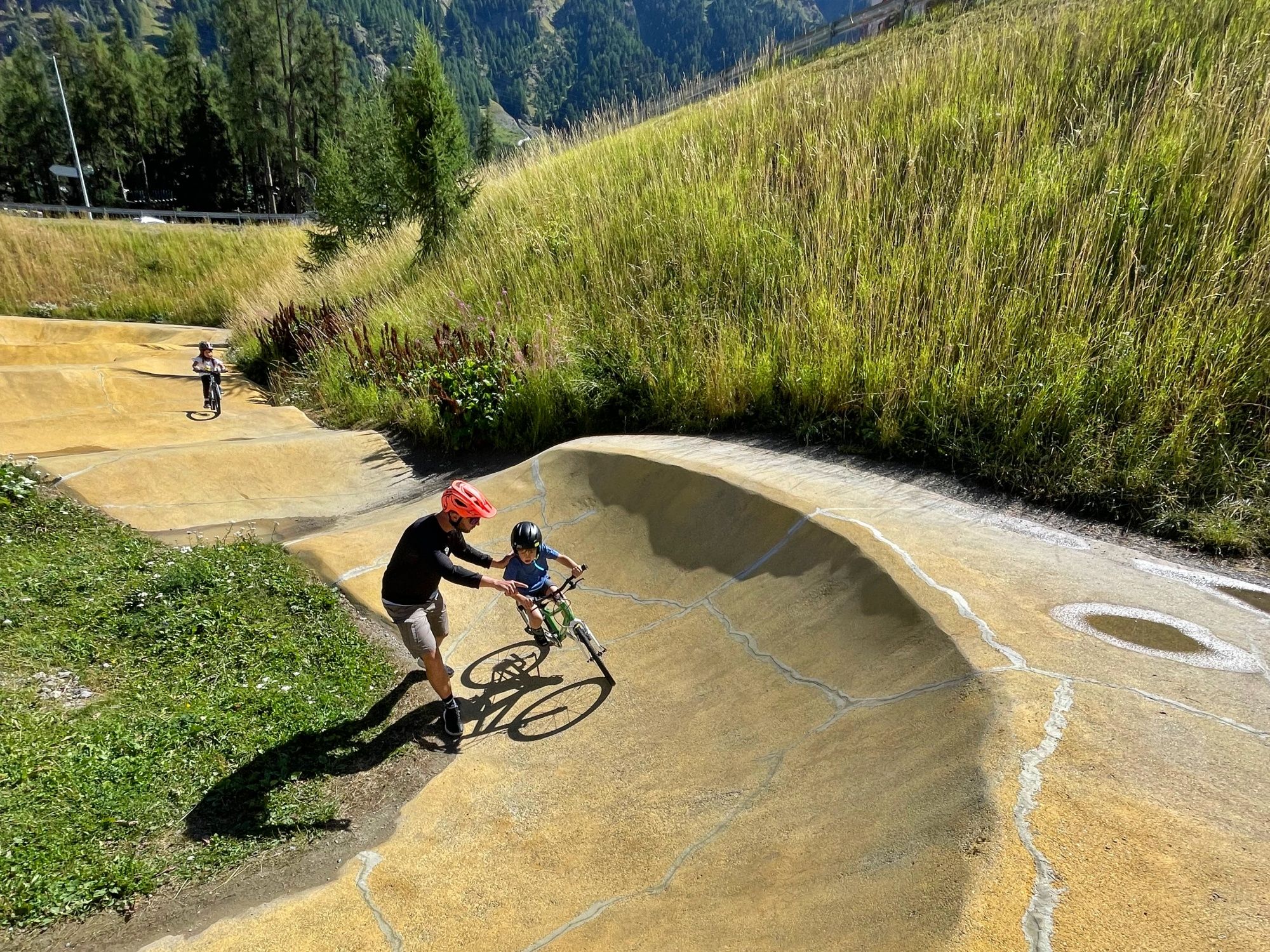 Obóz dla dzieci w St. Moritz: Mali uczestnicy bawią się na pumptracku rowerowym na łonie natury podczas lata.