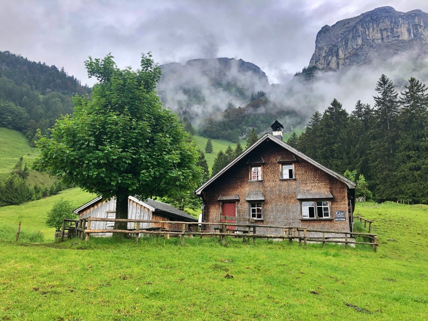 Alpstein: Rustikales Holzhaus in grüner Wiese unter Wolken.