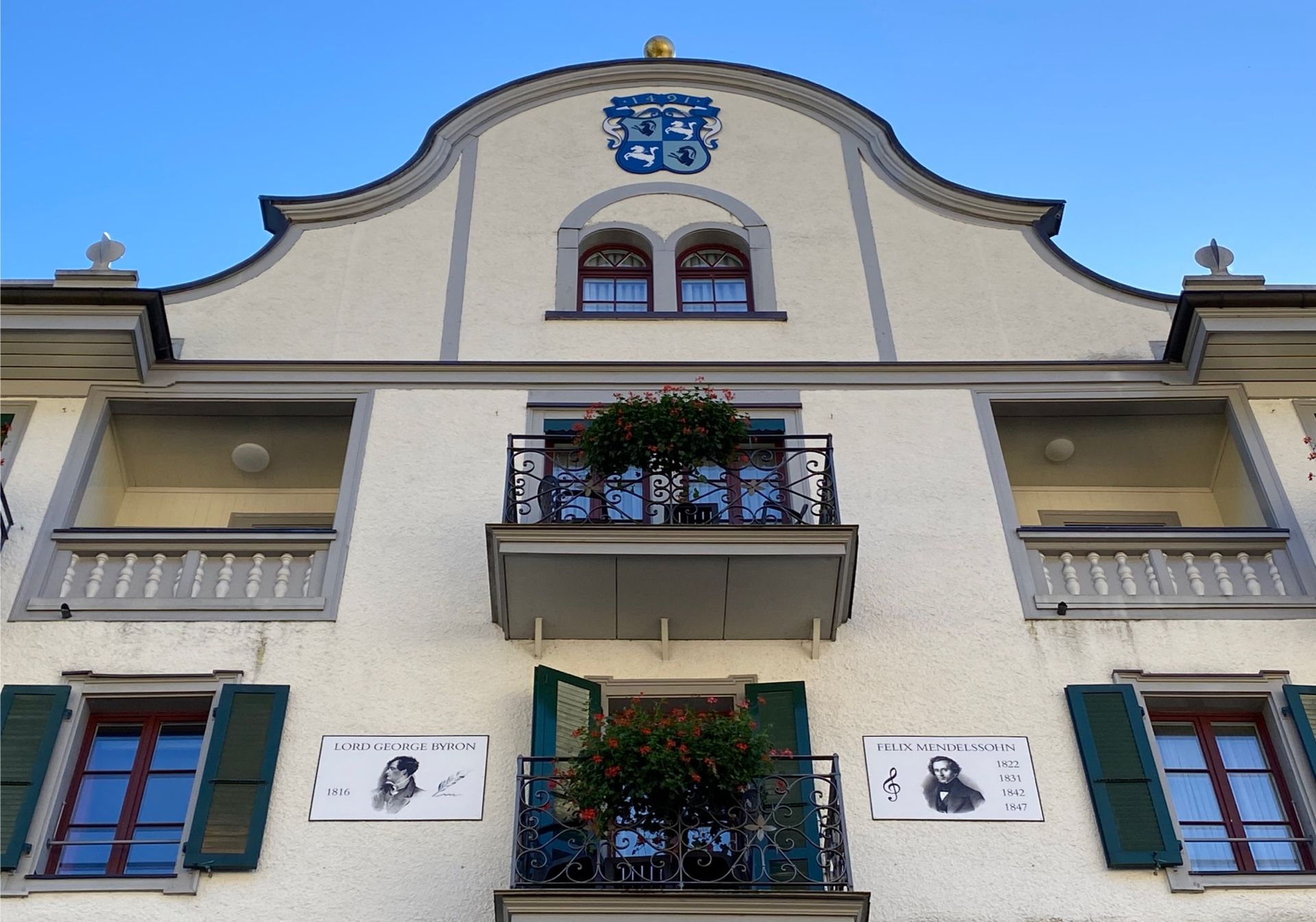 Explorial Interlaken: Zabytkowy budynek z artystycznymi detalami i pięknymi kwiatami.