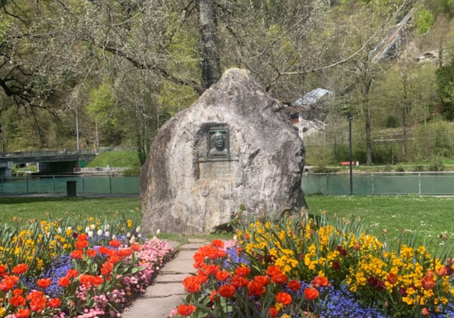 Explorial Interlaken: kolorowe kwiaty w parku przed pomnikiem na wiosnę.