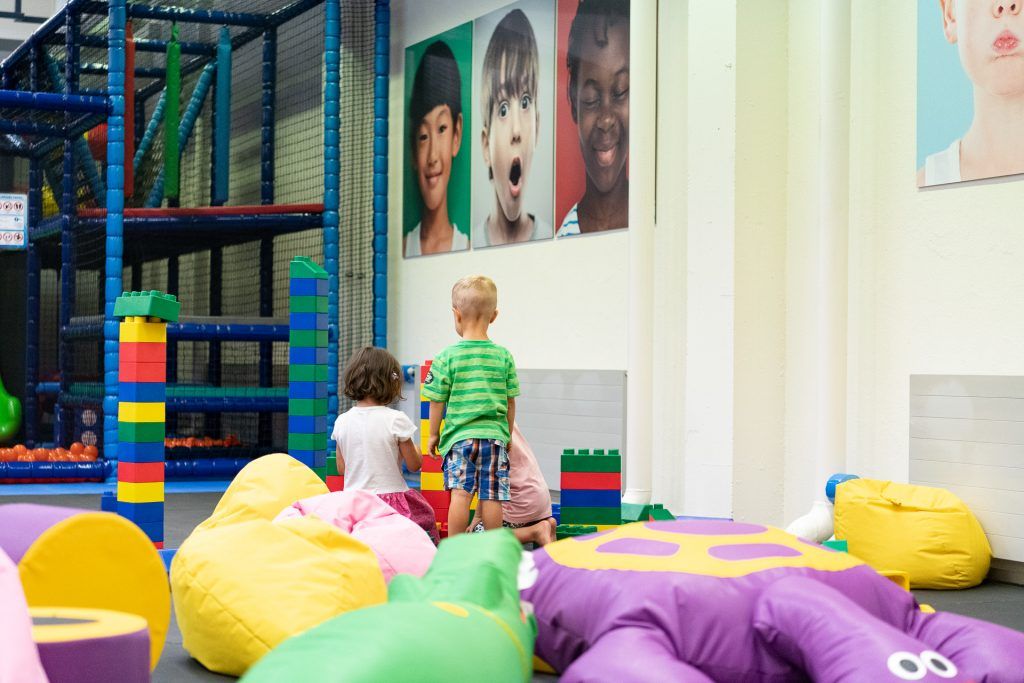 रंगीन कास्कबेलों और खेलने वाले बच्चों के साथ इनडोर खेल का मैदान