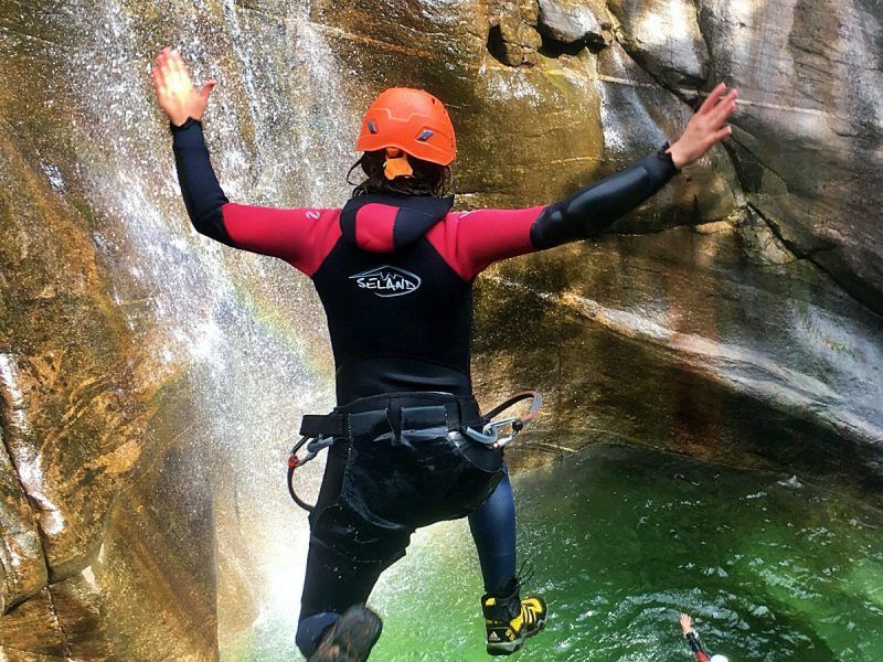 Iragna Canyoning, person jumps into the water, rocks, wetsuit