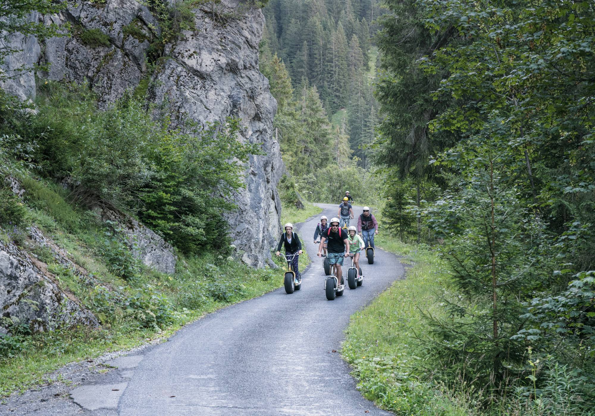 Monster scooter on the Alpine road near Isenfluh, group riding along green route.