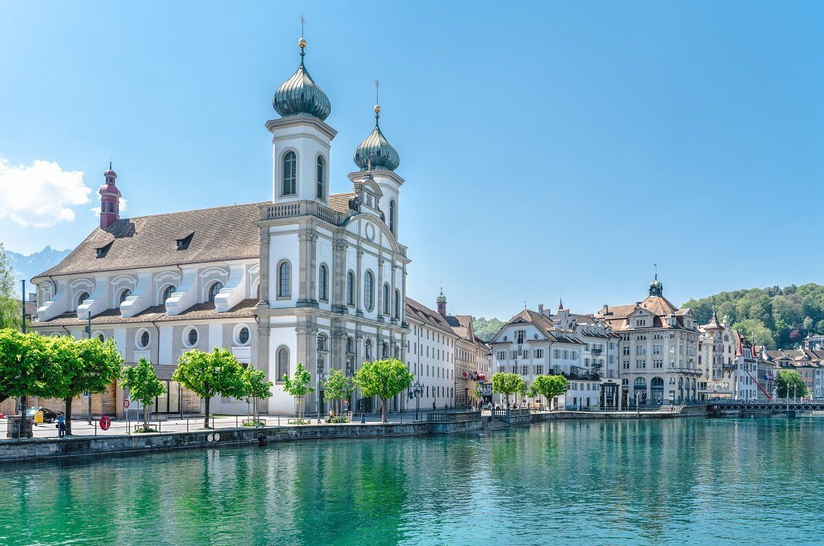 Jesuitenkirche Luzern mit grünen Bäumen und klarem Wasser